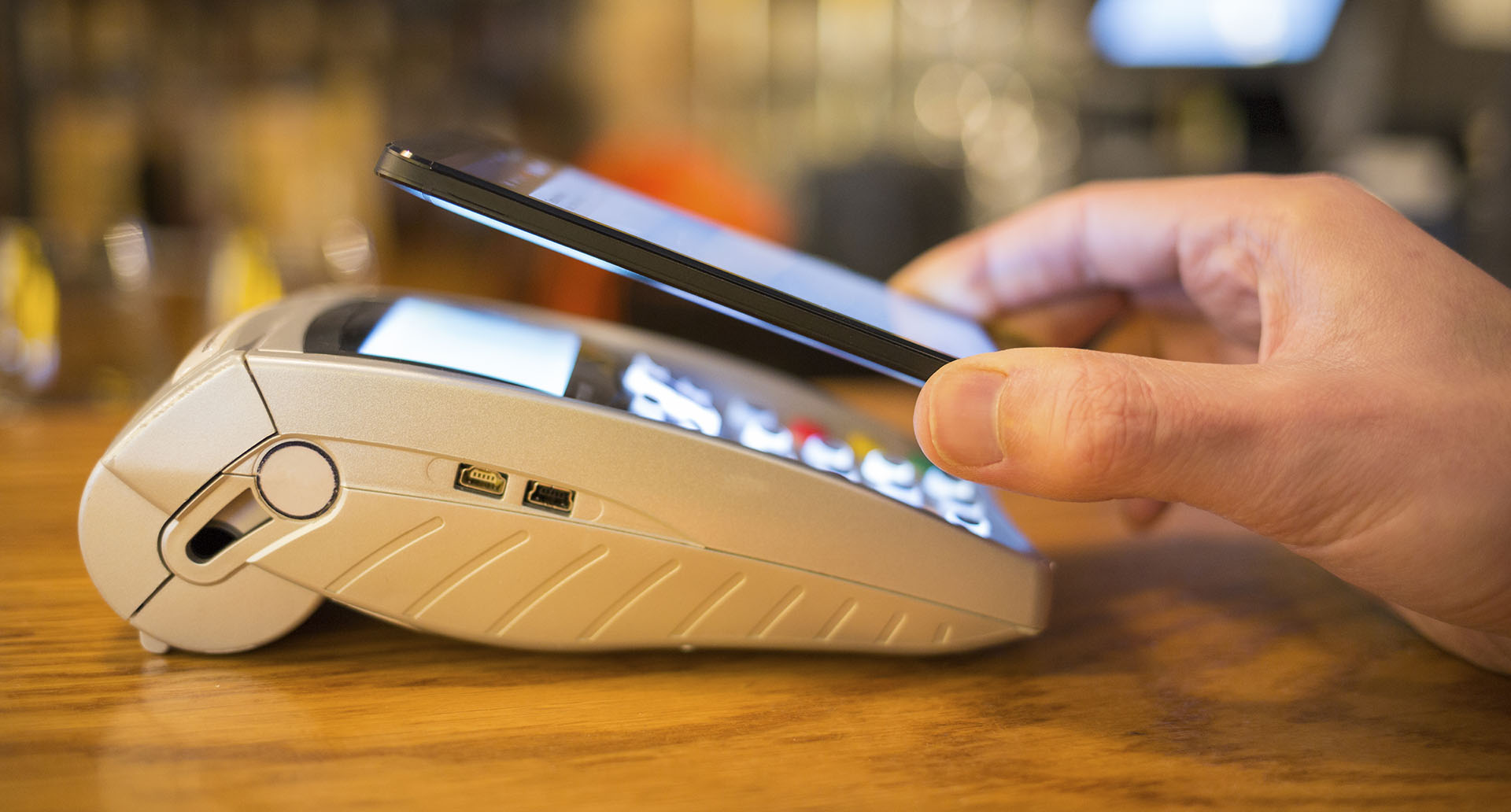 Man paying with NFC technology on mobile phone, restaurant, shop